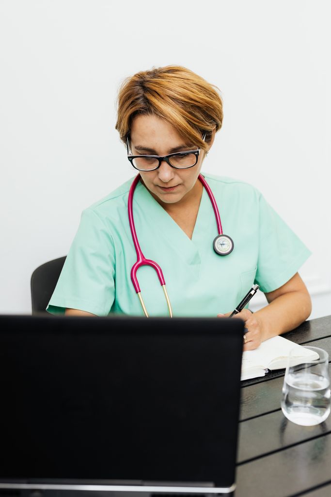 A healthcare professional or student looking at a computer wearing a stethoscope.