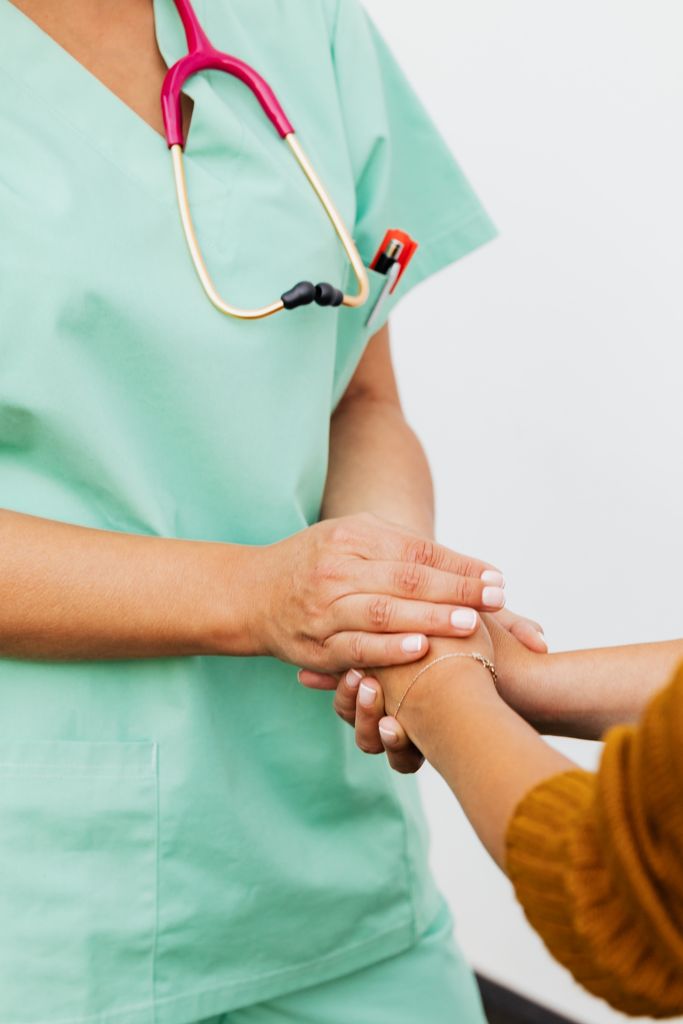 A healthcare professional or student holding hands in a caring professional manner with another person.